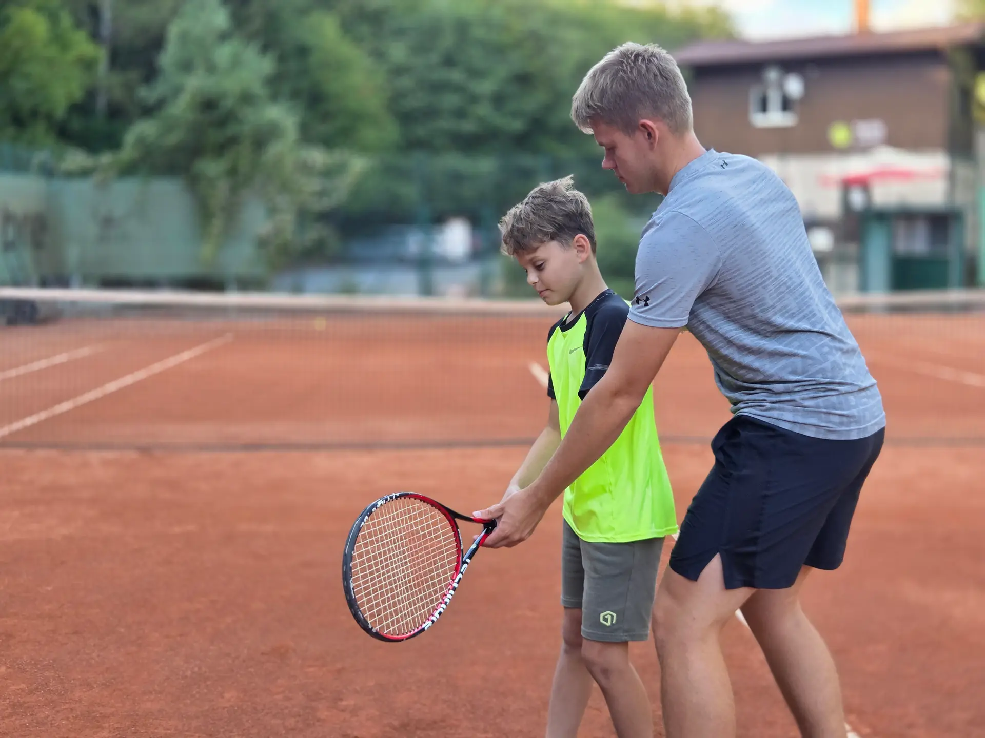 Václav Kvasnička učí chlapce tenisový úder na antukovém kurtu